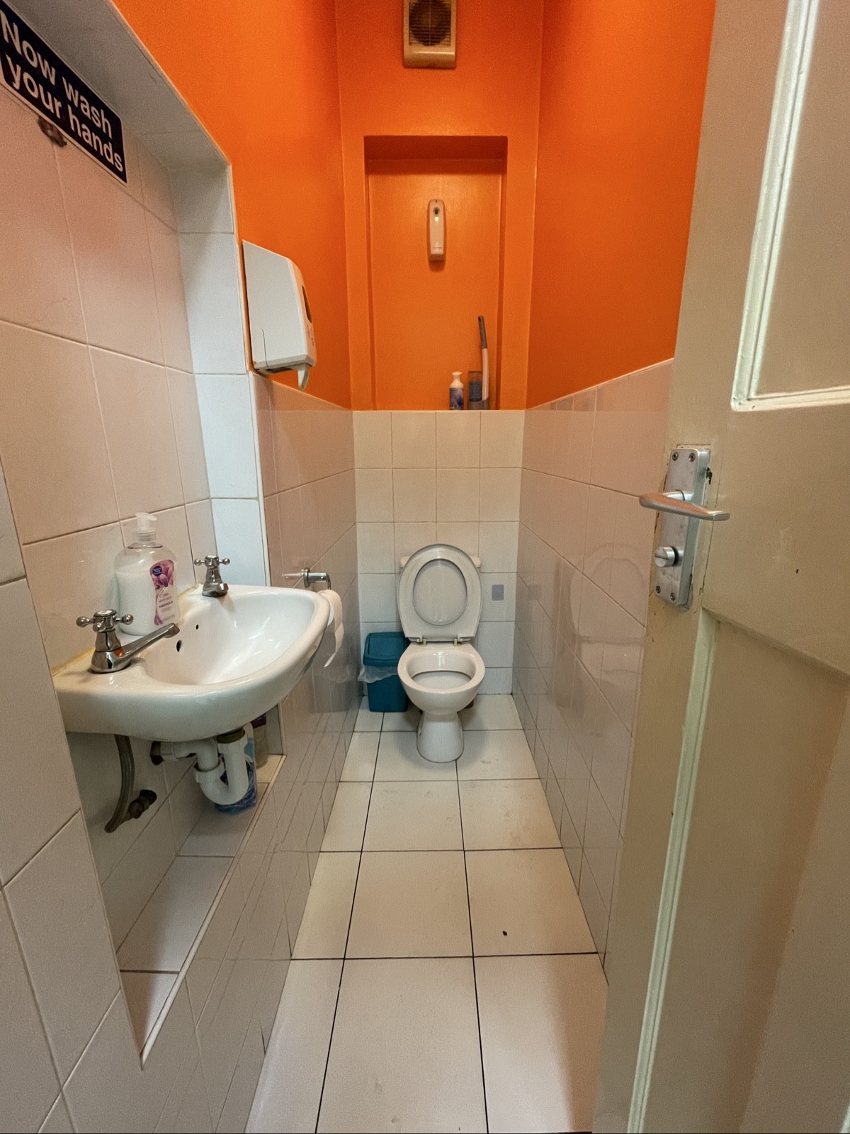 From door facing straight. Sink on left. Toilet at back.