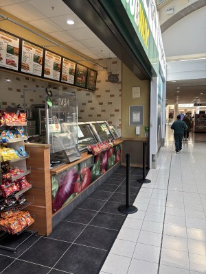 Opening ahead to kiosk counter along left. Mall on right.