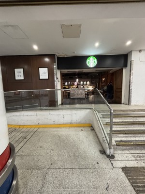 From station facing venue. Staircase on right to opening. Path ahead to ramp on left.