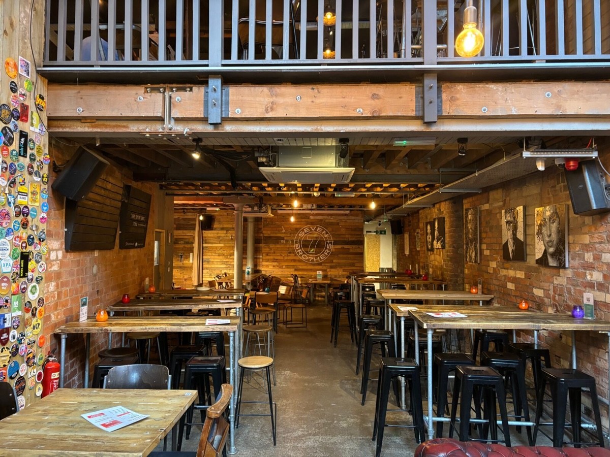 Photo shows the mixture of high and low tables, chairs and stools. The toilets are located to the left, next to the stairs.