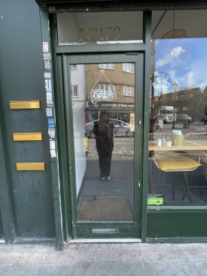 Facing glass door with green frame. Push on right to open.