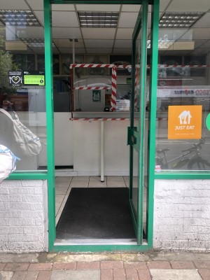 Glass door with green frame. Push handle on left to open.