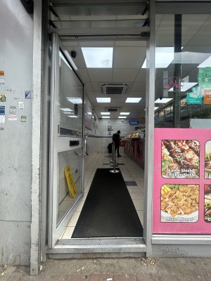 Glass door ahead with silver frame. Push silver handle on right to open.