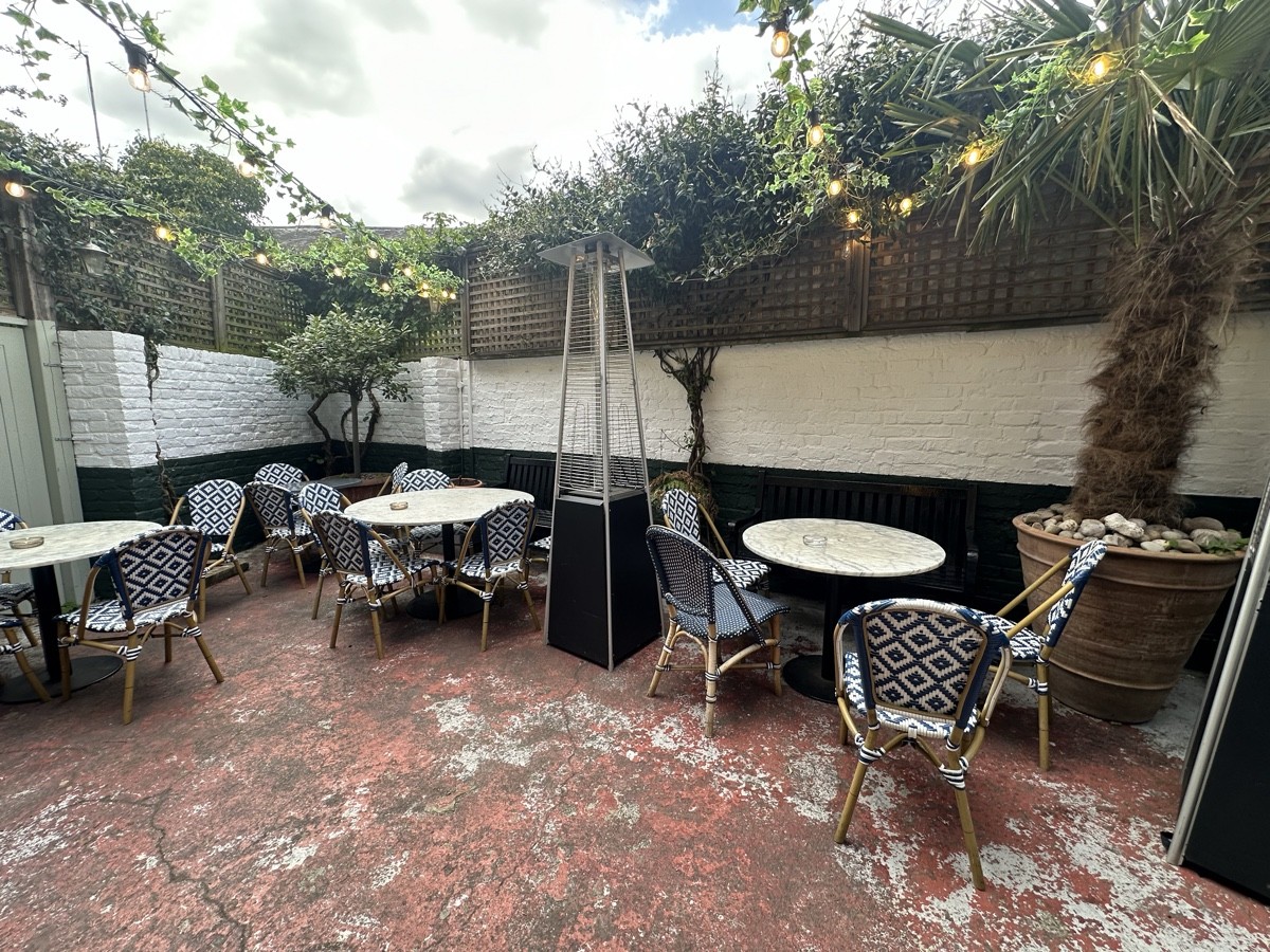 From bottom of steps facing straight. Tables and chairs along back. Heaters and planters in-between seating.