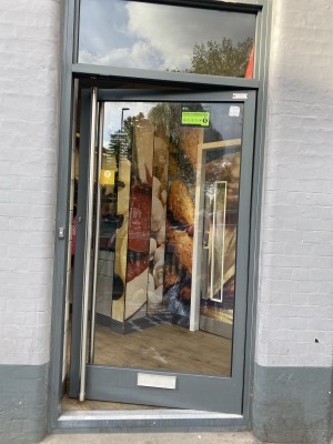 Glass door with grey frame ahead. Pull from handle on left to open