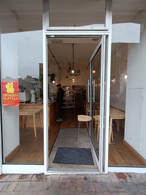 Glass door with white wooden frame. Push silver handle on left to open.
