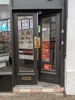 Glass doors with black frame and metal handles in centre. Push to open.