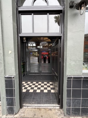 Black door ahead. Push from left to open.