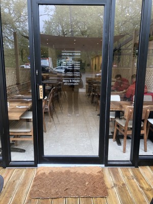 Glass door with black frame. Pull handle on left to open.