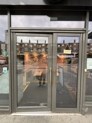 Glass doors with metal frames. Push from centre to open.
