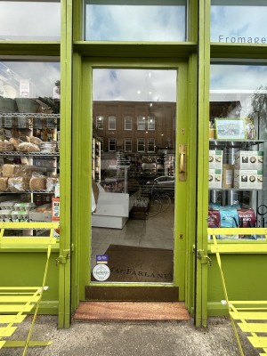 Glass door with green frame ahead. Push gold handle on right to open.