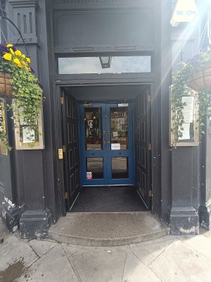 From street, facing venue. Step up to black wooden doors ahead. Push from middle to open. Doorbell on left doorframe.