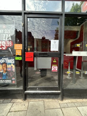 Glass door with black frame ahead. Push black handle on left to open.