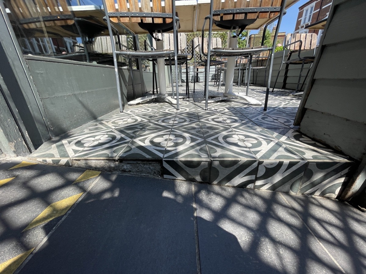 One step up to outdoor seating area. Step slopes up towards left.
