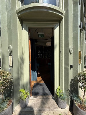 Glass door with brown wooden frame. Push from right to open.