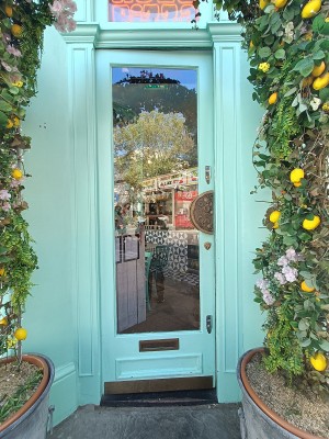 Glass door with green wooden frame. Push from right to open.
