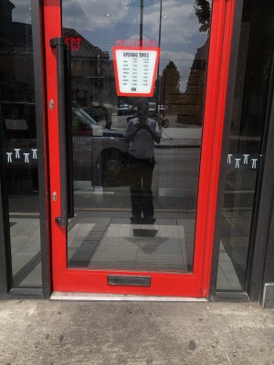 Glass door with red frame. Push handle on left to open.
