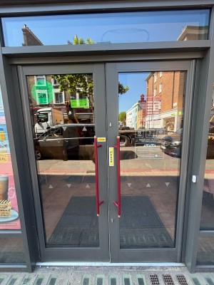 Glass doors with grey frames. Push red handles in centre to open.