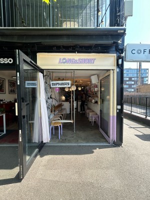 Glass doors ahead with yellow and purple frame. Pull yellow handle in centre to open.