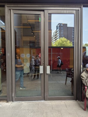 Glass doors with metal frame and metal handles. Pull or push from centre to open.