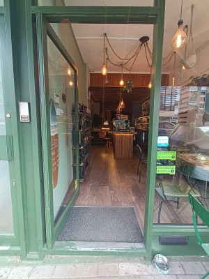 Glass door with green frames. Push from right to open.