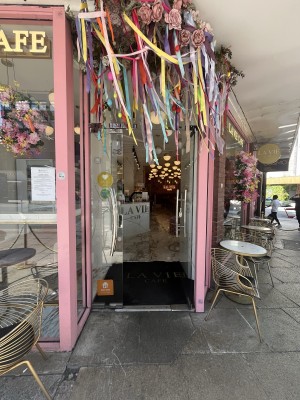 Glass doors with pink frame ahead. Push silver handles on centre to open door.