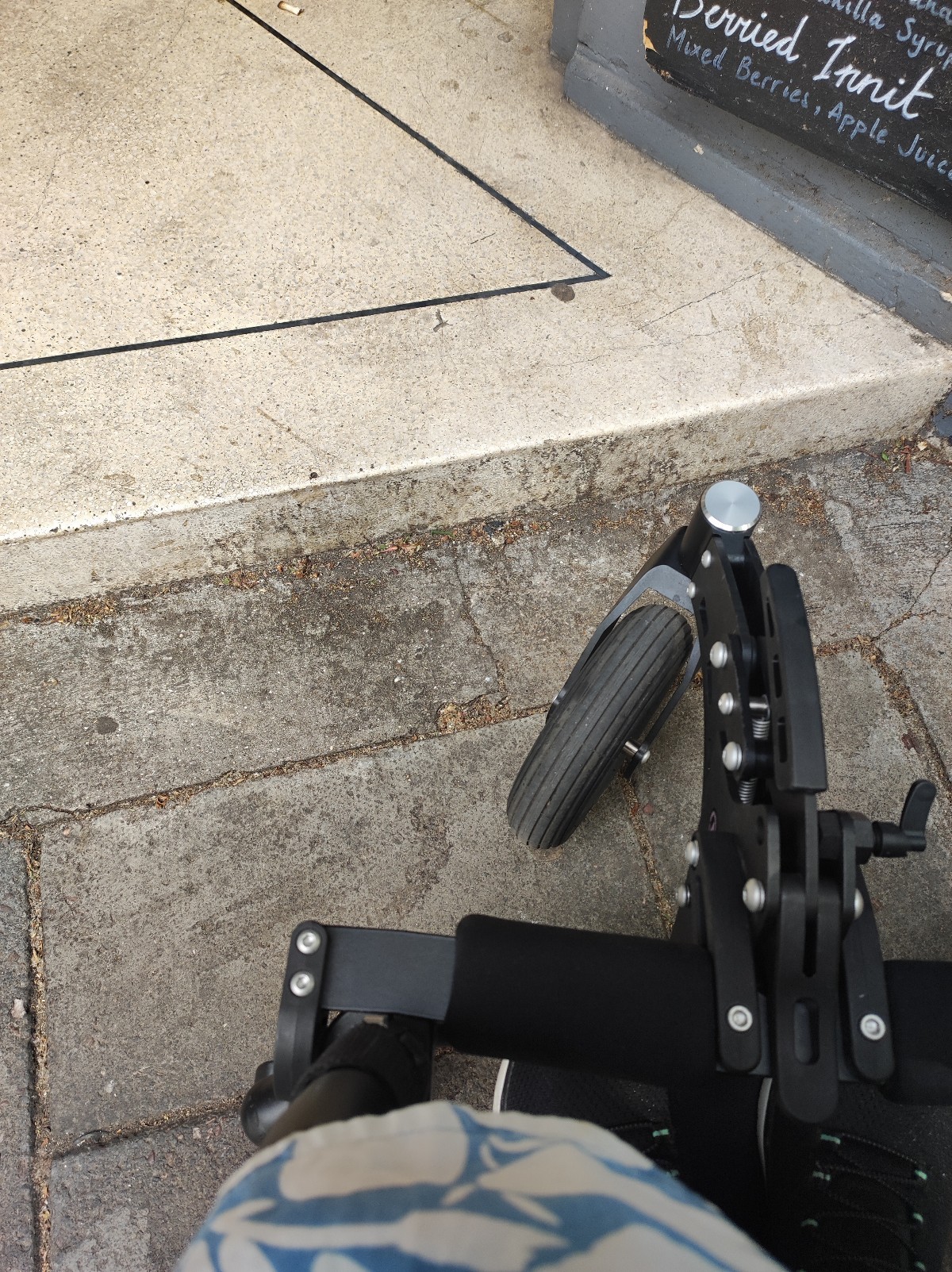 Image of initial white marble step for entry, next to wheelchair RGK Front Wheel for size comparison