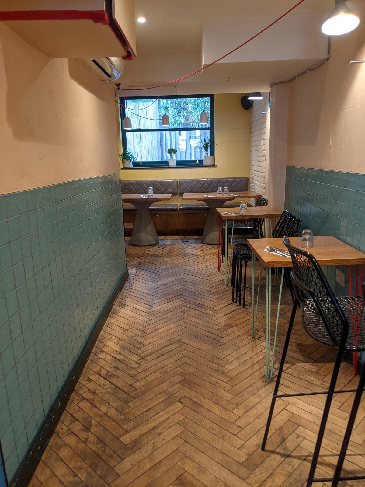 From after high table facing straight. Tables with chairs along right. Half booths at back.