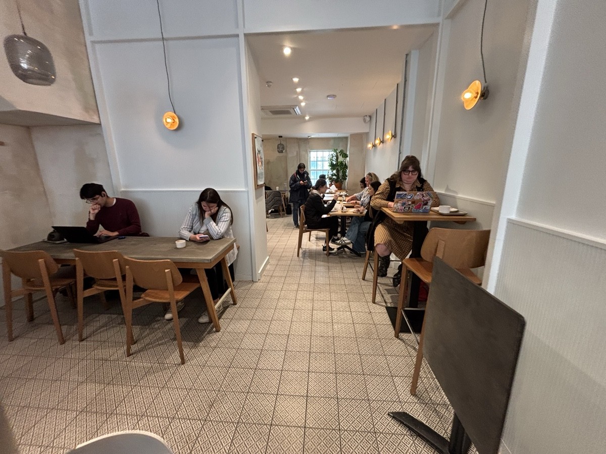 From end of counter facing straight. Table and chairs on left. Path in centre to back area. High table and stools on right.