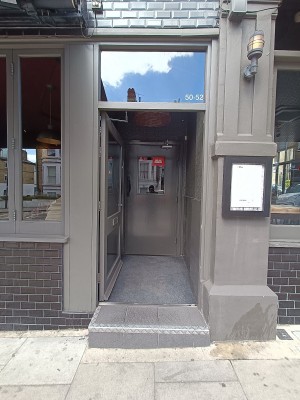 Glass door with grey, metal frame. Push from right to open.