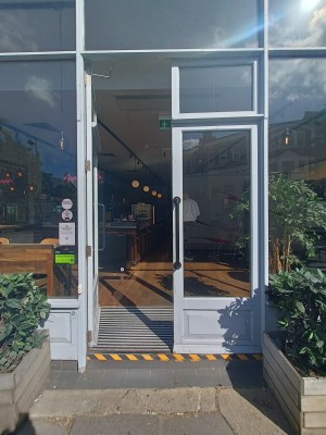 Glass doors with white, wooded frame. Push black handles in middle to open.