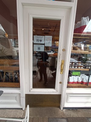 Glass door with white wooden frame. Push golden handle on right to open.