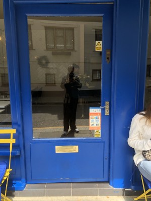 Glass door with blue frame. Push handle on right to open