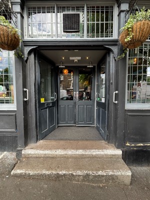 Two steps up to glass doors with black frames. Push from centre to open.