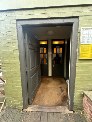From bottom of front outdoor area facing right. Grey door ahead. Push from right to open.