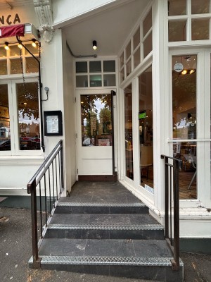 Three steps up ahead to door at the back. Black handrail on left.