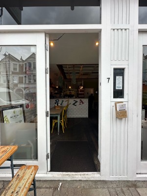 Glass door with white frame. Push from right to open.