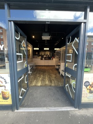 Glass doors with dark grey frame ahead. Push dark grey handles in centre to open.