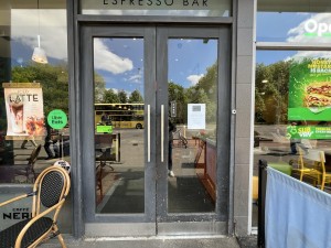 From sidewalk facing venue. Black and glass panelled doors. Push from metal handles in centre to open.
