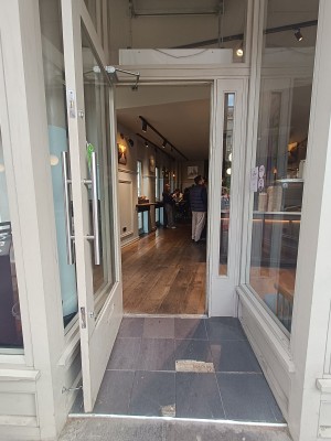 Glass door with white wooden frame ahead. Pull silver handle on right to open.
