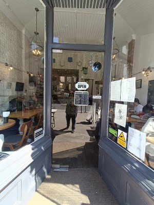 Glass door with grey wooden frame. Push silver handle on right.