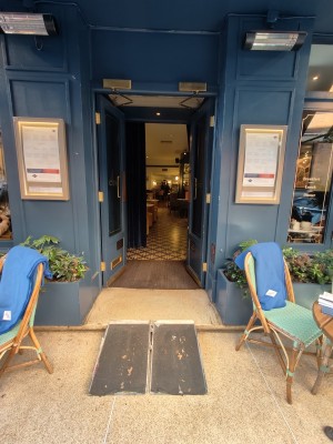 Ramp upon request going up to blue framed glass preceding doors. Push from centre to open.