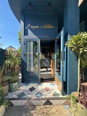 Blue and glass panelled doors. Pull silver handles from centre to open. Planters to left and right.