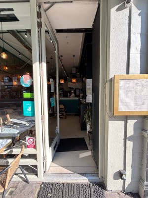 A glass door with grey frames. Push from right to open.