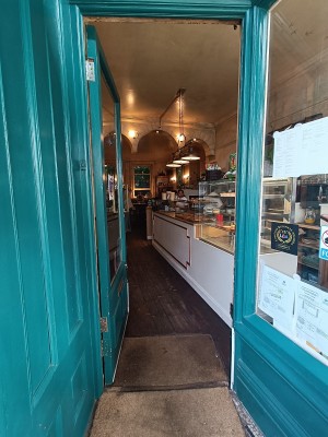 Glass door with green wooden frame. Push golden handle on right to open.