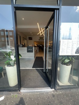 Black framed glass door ahead. Push from metal handle on left to open.