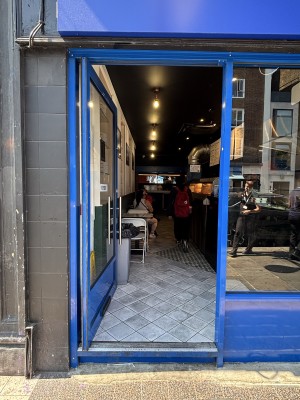 Glass door with blue frame. Push from right to open.