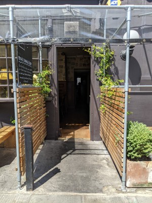 From after outdoor seating facing left. Opening ahead with metal scaffolding.