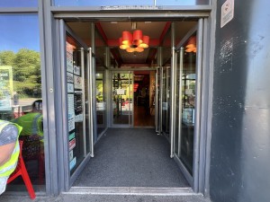 Grey framed glass preceding doors. Push from metal handles in centre to open.