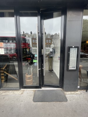 Glass doors with black frame ahead. Push silver metal handles from centre to open.